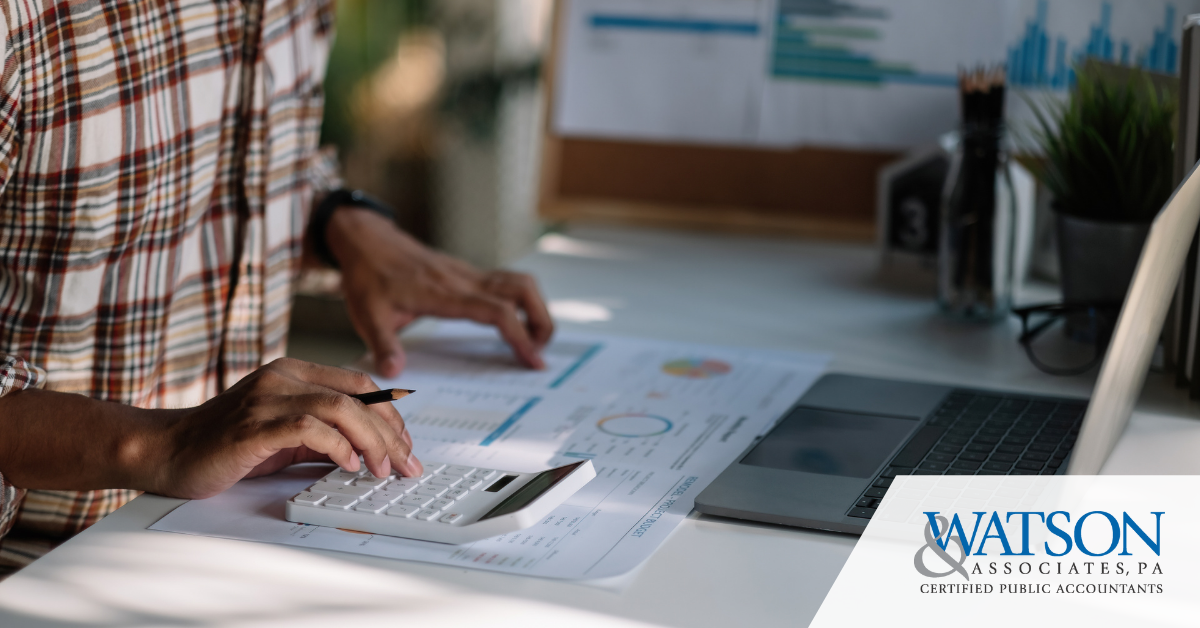 Business owner working on business taxes | Watson & Associates logo