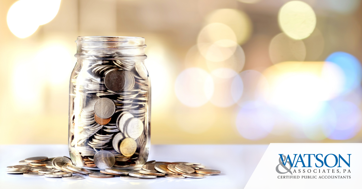 Year end giving - Jar of money filled with coins and Watson & Associates logo in the bottom right corner.